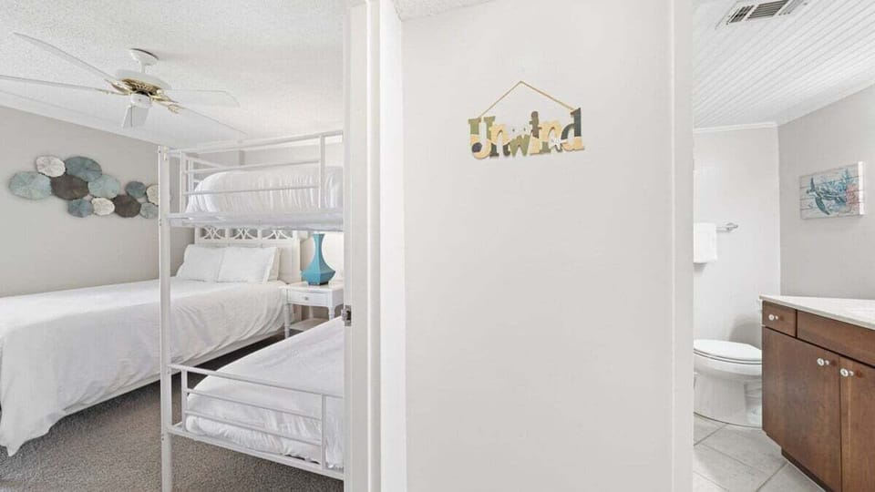 Family-friendly bedroom with queen bed and twin-over-twin bunks—perfect for kids or extra guests. Light, bright, with beachy accents and nearby full bathroom.