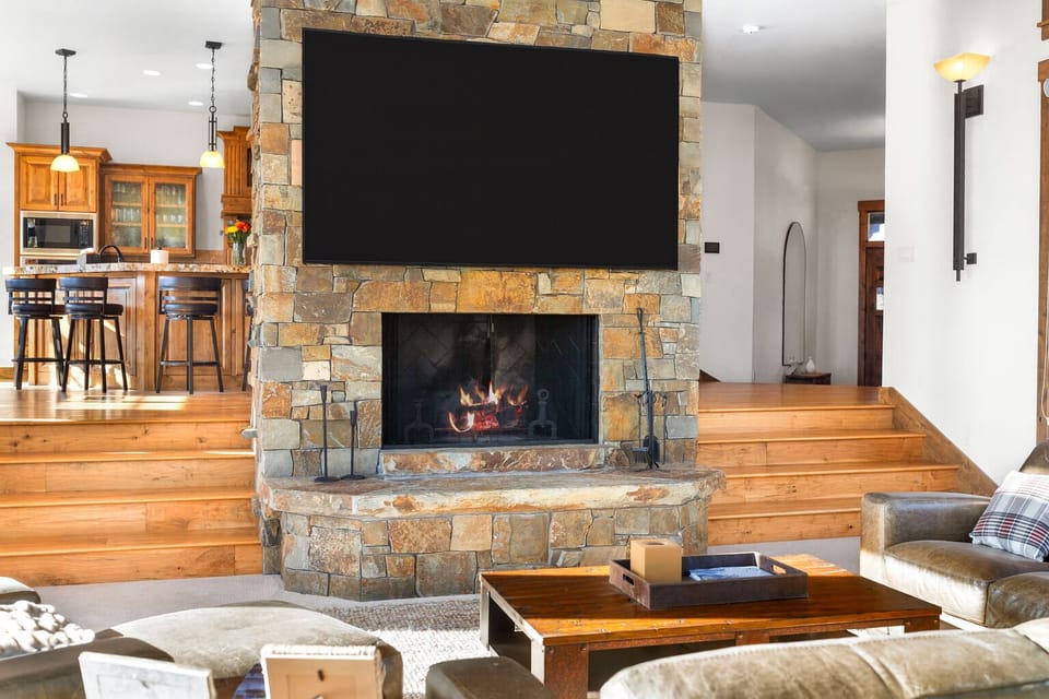 Cozy great room with stone fireplace, big TV, and open kitchen bar