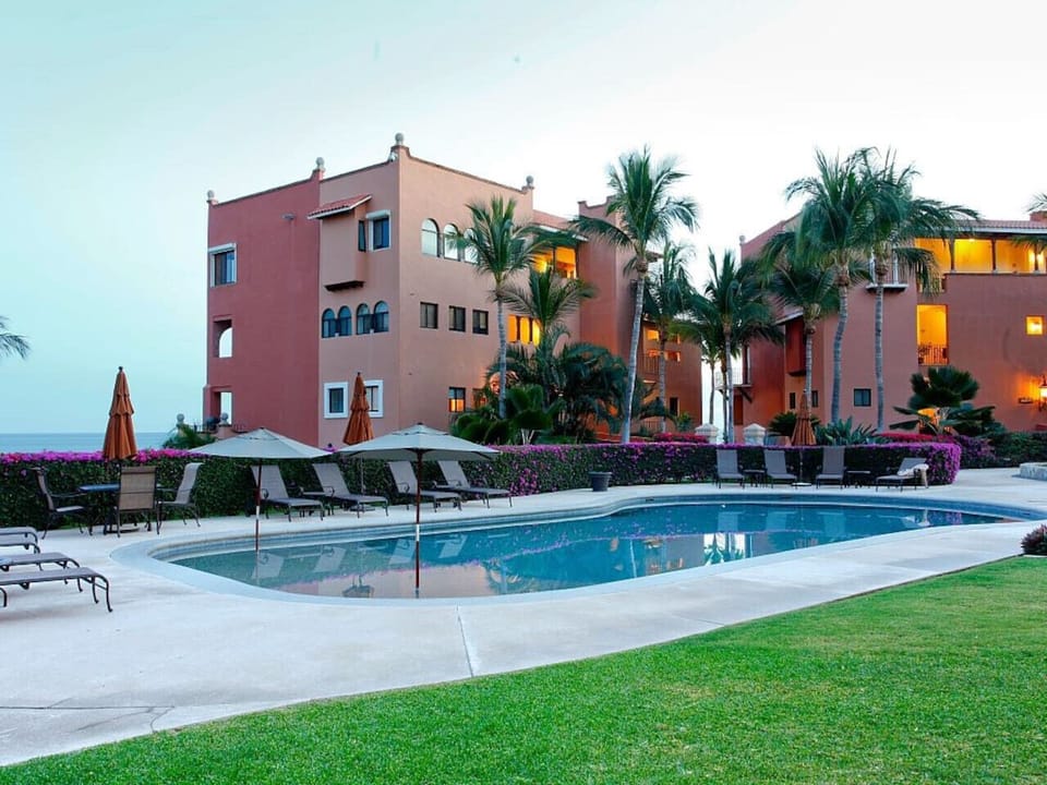 Pool and Building Exterior – Scenic view of the pool area framed by landscaped gardens and terracotta buildings.
