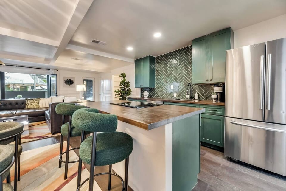 Stylish bar seating with plush green chairs at the kitchen island, perfect for casual meals or chatting with the chef.