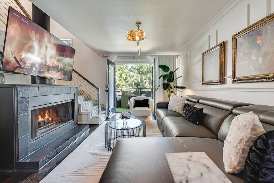 The spacious living room boasts an inviting fireplace and an open-concept design, with a massive TV and leather sectional, serving as the focal point for both relaxation and entertainment.
