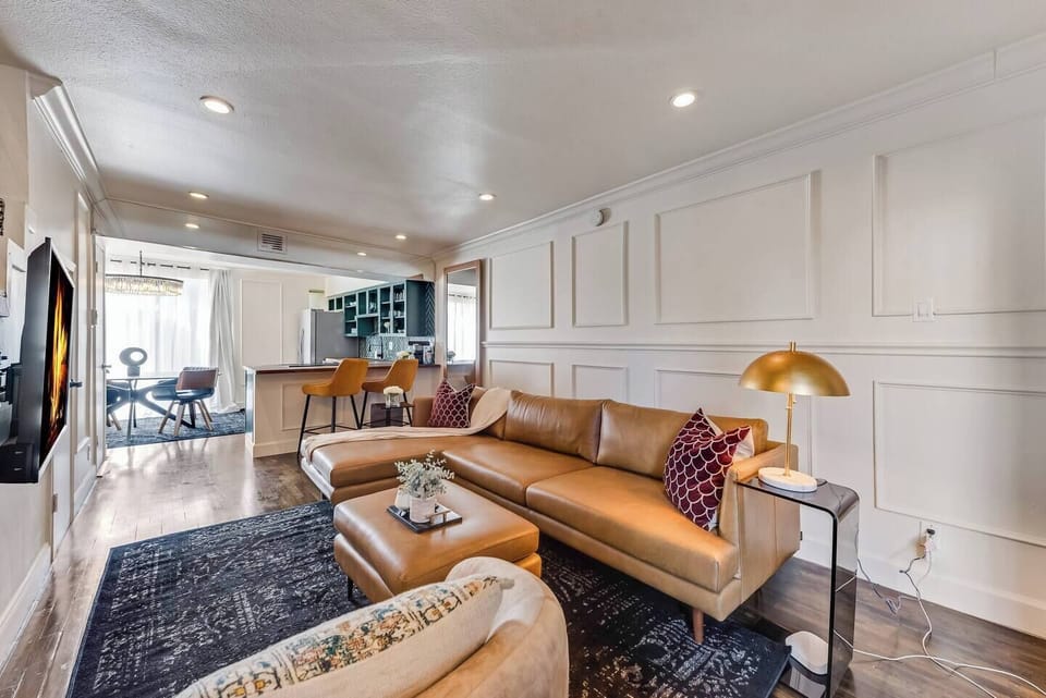 Spacious living room with a smart TV and a large leather sectional, perfect for relaxing and enjoying your favorite shows.