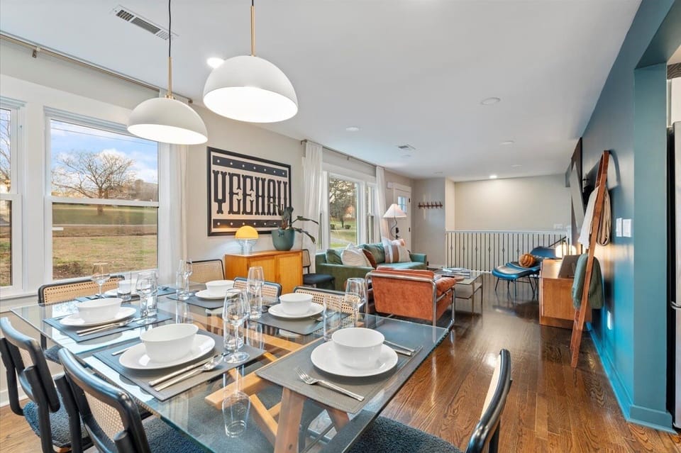 Dining area with glass table for eight, bold artwork & warm natural light.