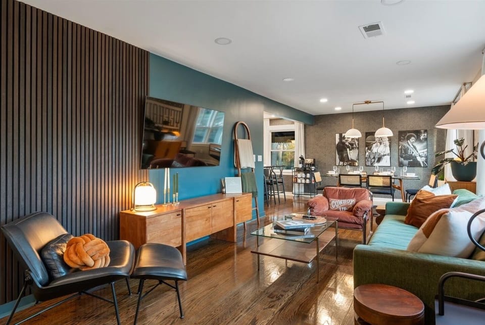 Bright living room with wood wall, green sofa, leather lounger & TV.