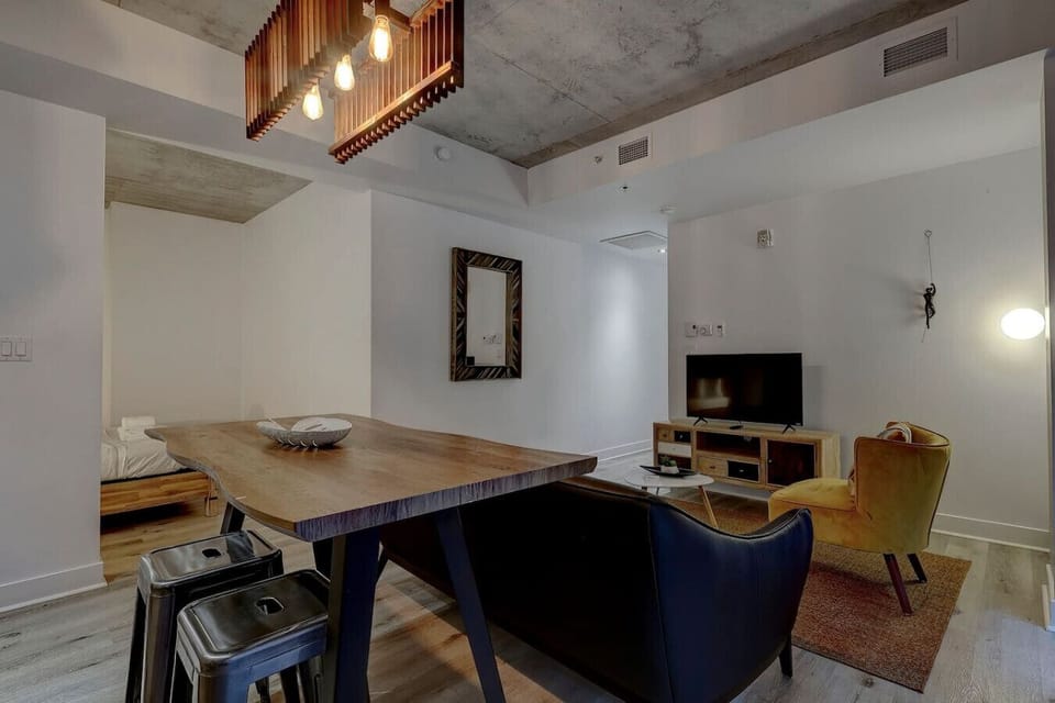 Chic and inviting dining area with industrial-inspired lighting, a spacious wooden table, and a cozy lounge setup for an intimate experience.