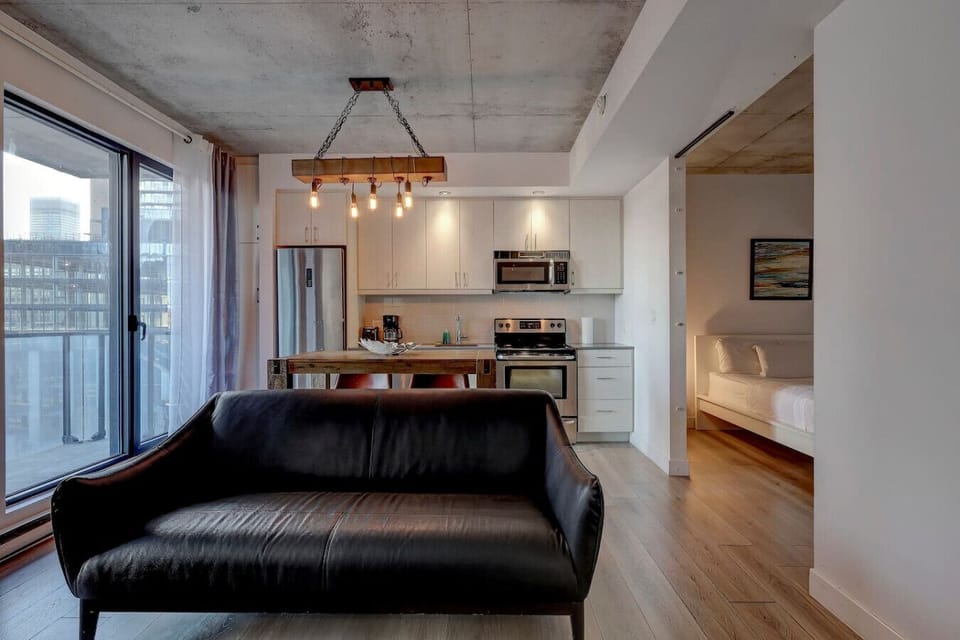 A seamless blend of comfort and style, with a plush black leather sofa and open layout extending into the sleeping area.