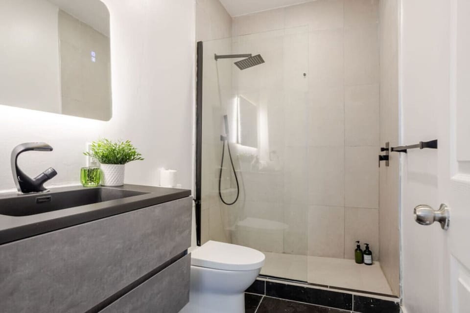 Bathroom: Sleek rainfall shower and modern vanity in a bold monochrome palette