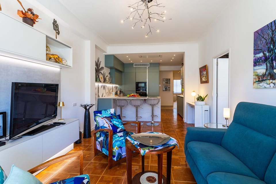Spacious living room with a modern open kitchen, featuring cozy seating and colorful decor. Perfect for a relaxing and enjoyable stay.