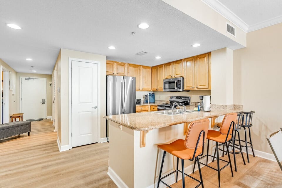 Cook and entertain in this stylish, fully equipped kitchen featuring granite countertops, stainless steel appliances, and a spacious breakfast bar with comfortable seating