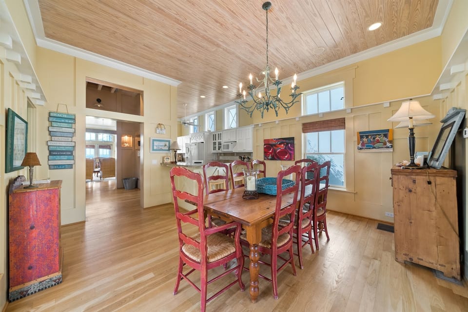 Gather around this rustic dining table where warm wood beams frame memorable meals together under elegant chandelier lighting.