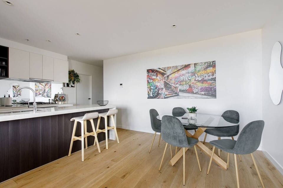 Connect over meals at the glass dining table for five, set against bold urban artwork that adds a touch of Melbourne’s culture.