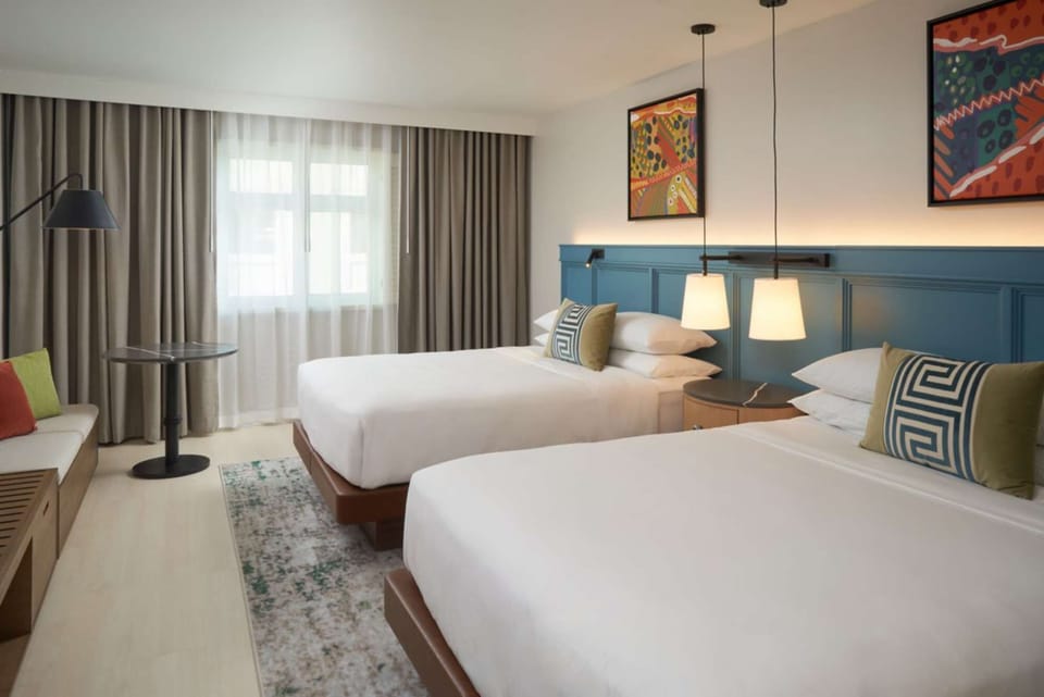 Bright room with two beds, blue wall panel and hanging lights