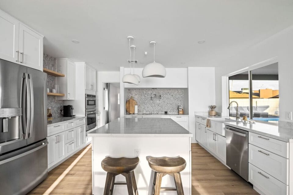 Sleek white kitchen with stainless steel appliances and generous counter space.