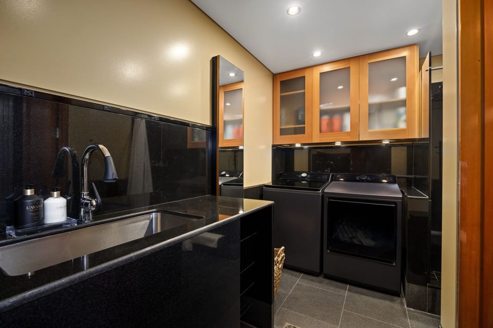 Compact laundry room with sleek black countertops and ample storage.
