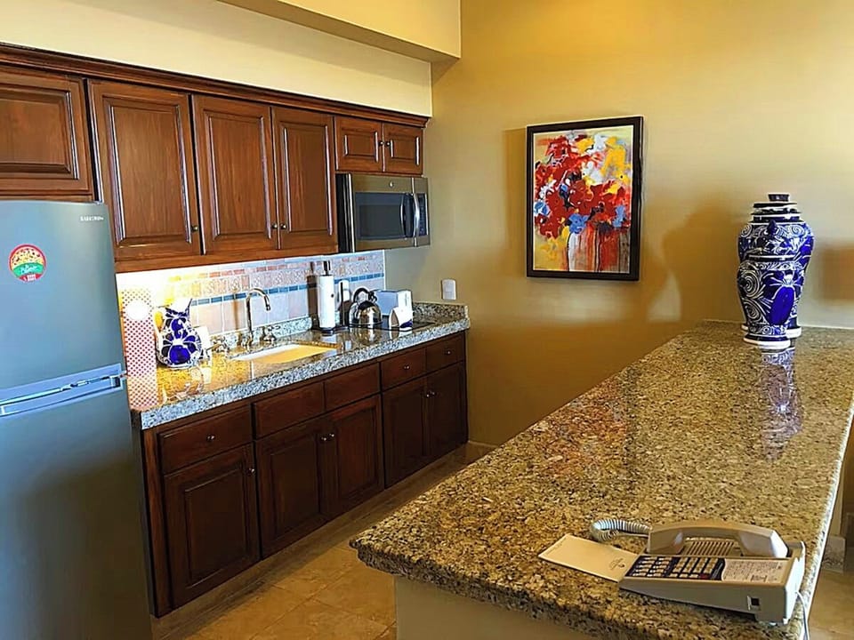 Kitchens equipped with fridge, microwave, stovetop, toaster, blender and dishes.