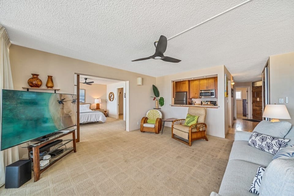 Living room in the first unit with ocean views, large TV, and spacious seating. Master bedroom is shown off the living room with sliding doors for privacy