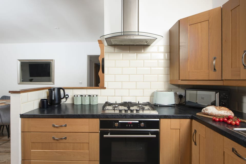 Kitchen with electric oven and hob, dishwasher, microwave, fridge/freezer, kettle, toaster and a range of pans and utensils.