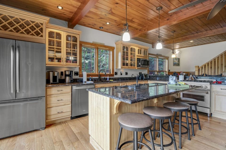 Modern, fully equipped kitchen featuring breakfast bar, custom cabinetry, and natural light.
