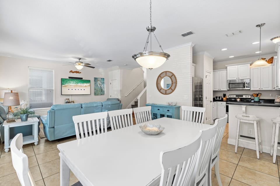 Relax in this bright open-concept space where coastal blues meet crisp whites, creating your perfect gathering spot for meals and memories.