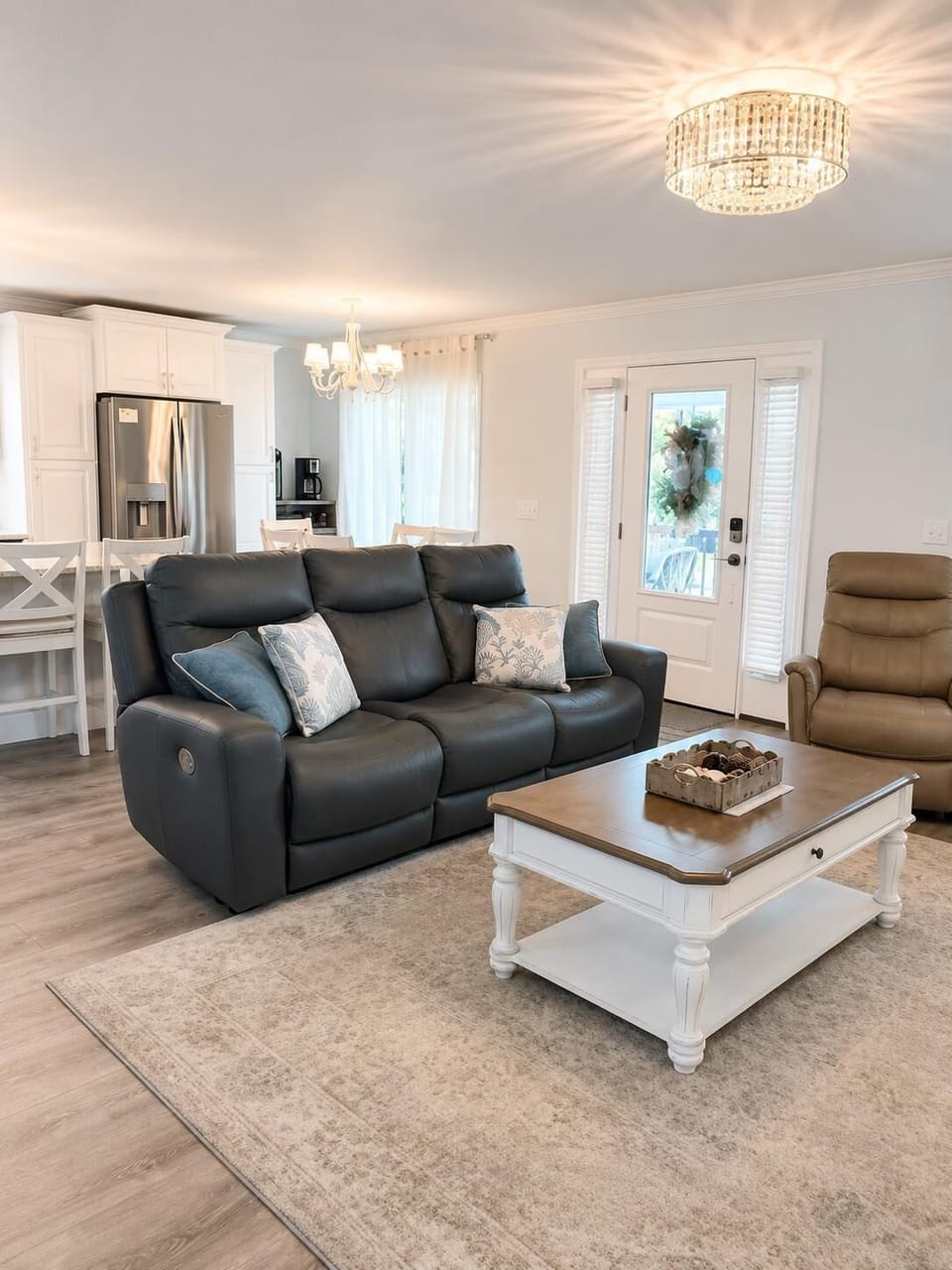Living room with dark leather sofa, beige recliner, white and wood coffee table, and hardwood flooring.