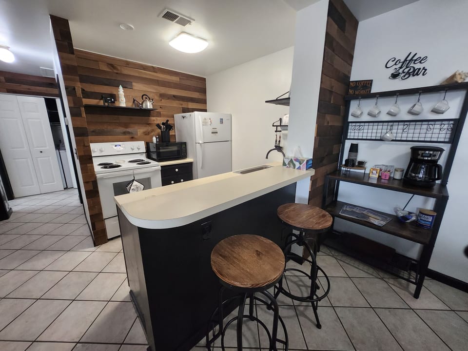 Kitchen, bar with stools, and stocked coffee bar