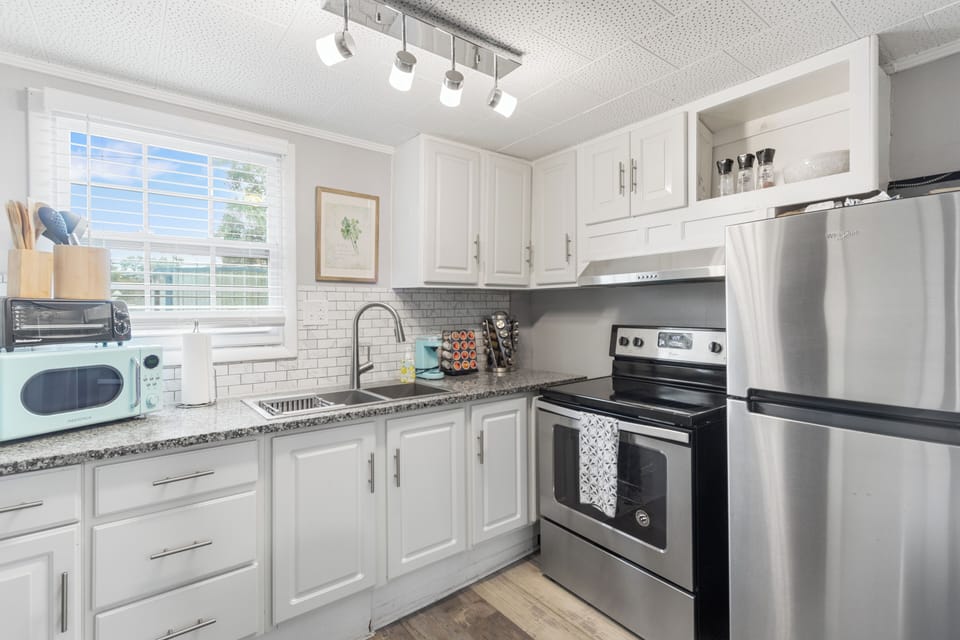 The kitchen is flooded with natural light and features a beautiful backsplash, modern cabinetry, and handy appliances.

