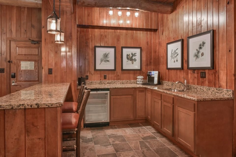 Charming kitchenette with rich wooden cabinetry, granite countertops, and elegant lighting for a delightful cooking experience.