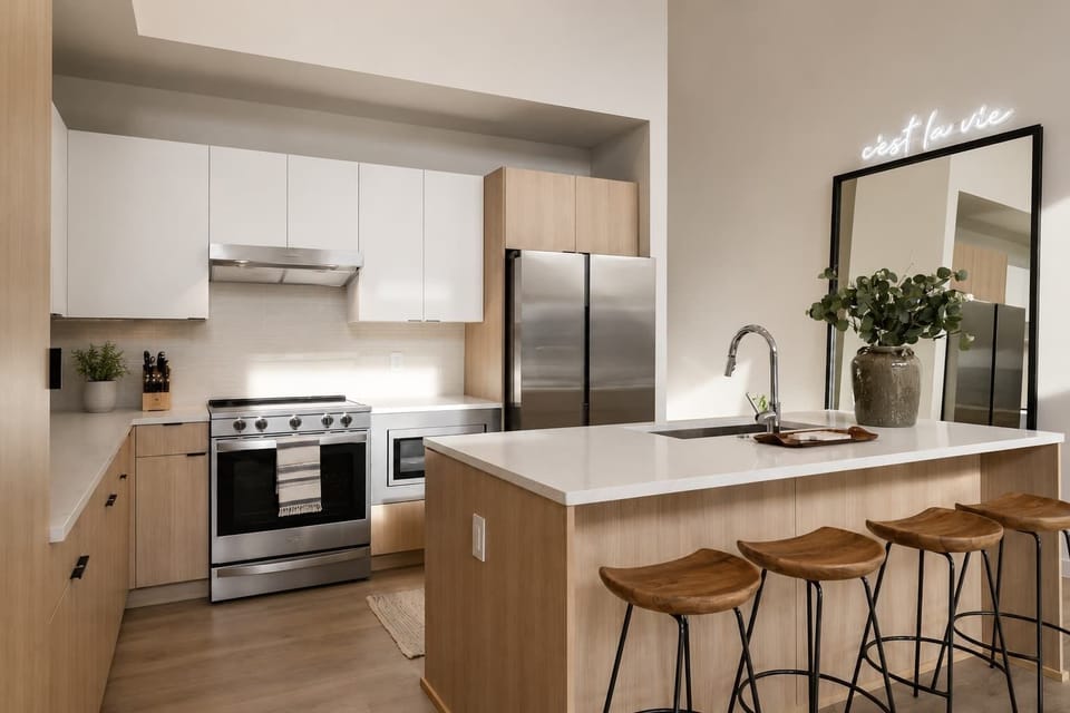 Stylish and functional tall ceiling kitchen with stainless steel appliances, full size mirror and natural wood accents.
