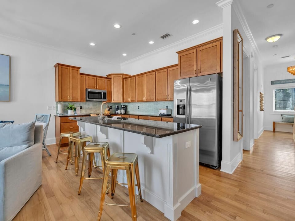 Your fully equipped kitchen features warm wood cabinets, granite counters, and a breakfast island where you can sip morning coffee.