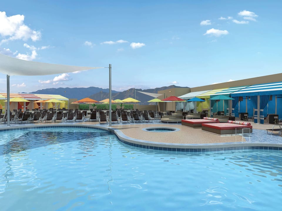 Lounge poolside under bright umbrellas and mountain views.