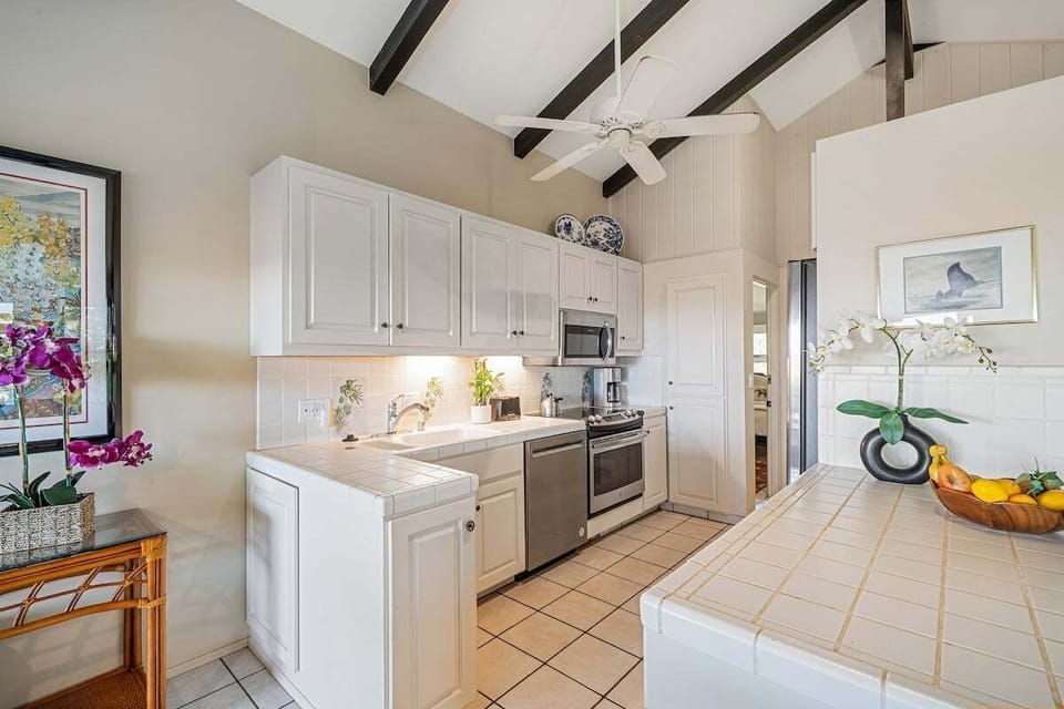 Spacious kitchen, with tiled counter, white cabinetry and stainless steel appliances