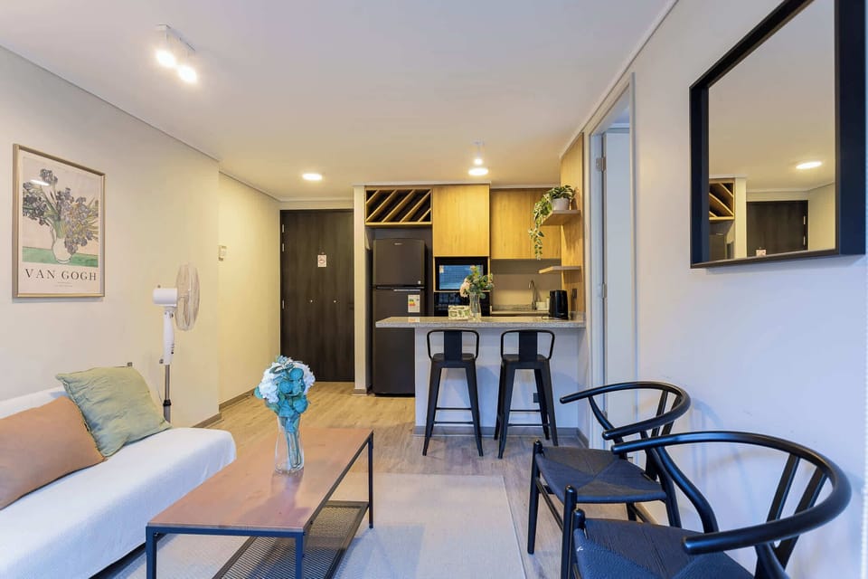 Chic living space with a cozy sofa and modern kitchen, perfect for relaxing or entertaining.