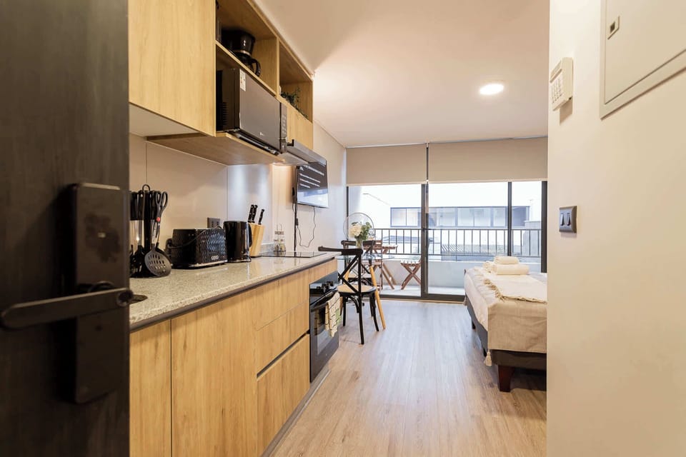Cozy studio apartment with a modern kitchen and balcony access, perfect for a relaxing stay in the heart of the city.