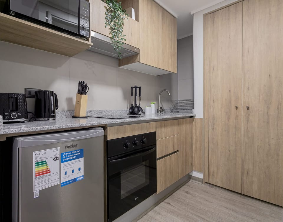 Modern and fully-equipped kitchenette perfect for a cozy stay, featuring sleek appliances and stylish wooden cabinetry.