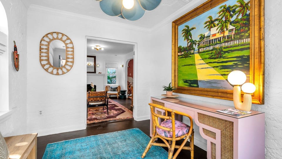 Work meets charm! The entry den features a spacious desk and chair for a dedicated workspace with high-speed internet, all framed by the home's stunning original 1920s front door.
