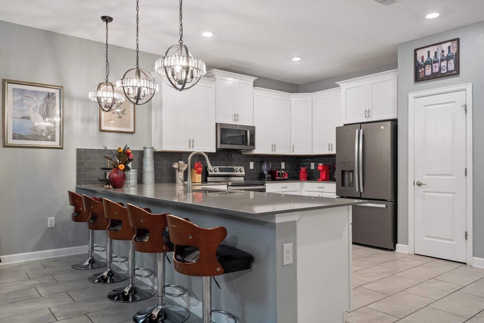 Sleek modern kitchen with stylish lighting, stainless steel appliances, and island seating!