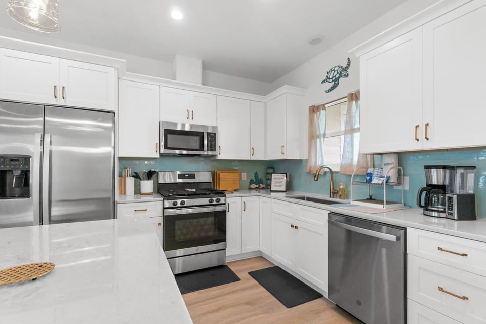 Your bright, coastal kitchen awaits with stainless steel appliances and turquoise backsplash creating a beachy, homey vibe.