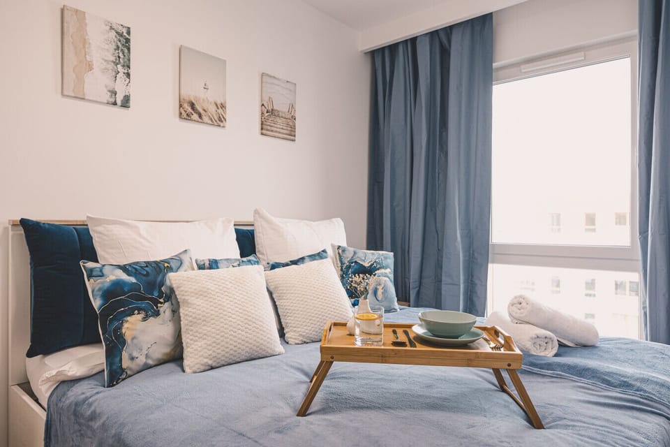 A cozy bedroom in a loft style, adorned with marine colors and beautiful artwork. The spacious, comfy bed promises restful nights, while the window view reminds you the beach is just 50 m away. Perfect for dreaming and serene mornings.