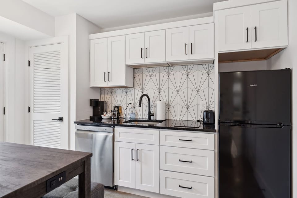 Kitchen: Stylish kitchen with black granite countertops, geometric backsplash, stainless steel appliances, and ample cabinet storage.
