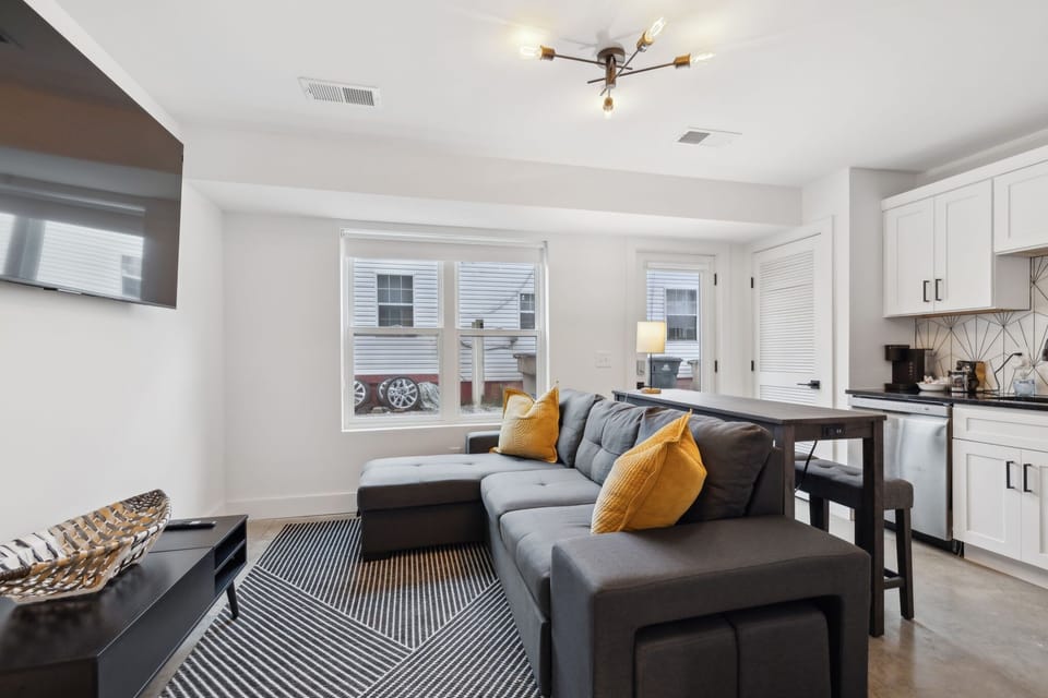 Living Room: Spacious living area with a wall-mounted TV, modern light fixtures, and a large sectional sofa for family gatherings.