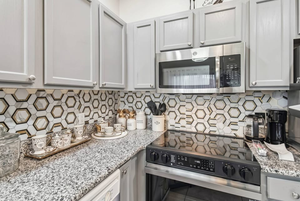 This stylish kitchen boasts a striking honeycomb backsplash that adds contemporary flair, while sleek gray cabinetry and polished granite countertops create a perfect space for your culinary adventures.