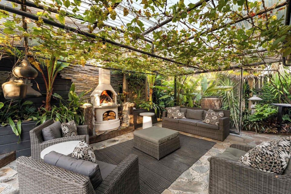 Tranquil outdoor living area with fireplace and spa set amongst tropical planting and beautiful sculptures   