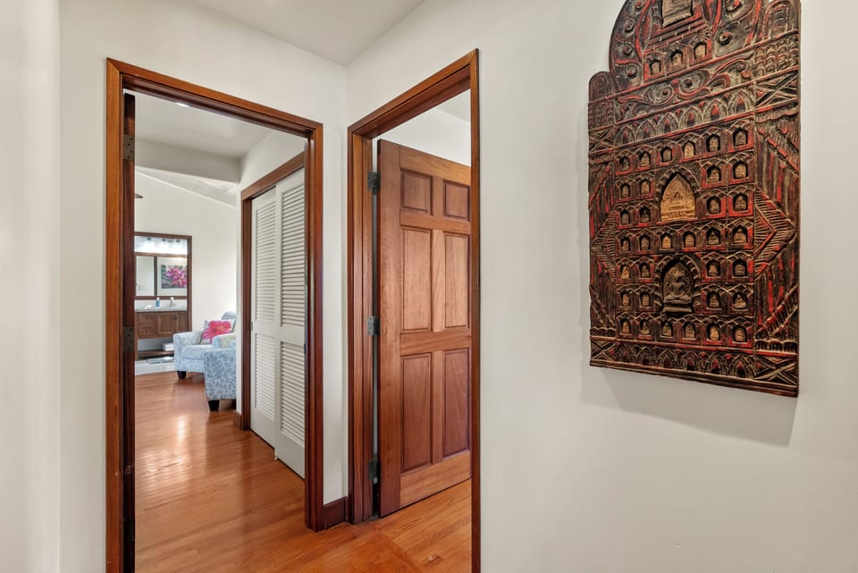 A bright hallway leading to private retreats, featuring island-style artwork and warm wood accents.