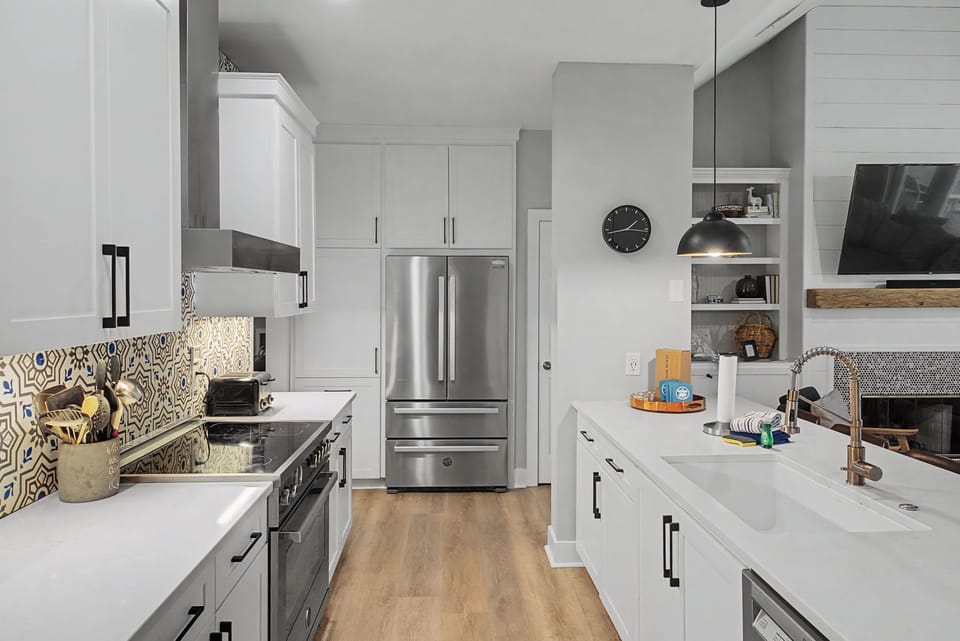 A full suite of stainless steel appliances pairs beautifully with crisp white cabinetry and quartz countertops.