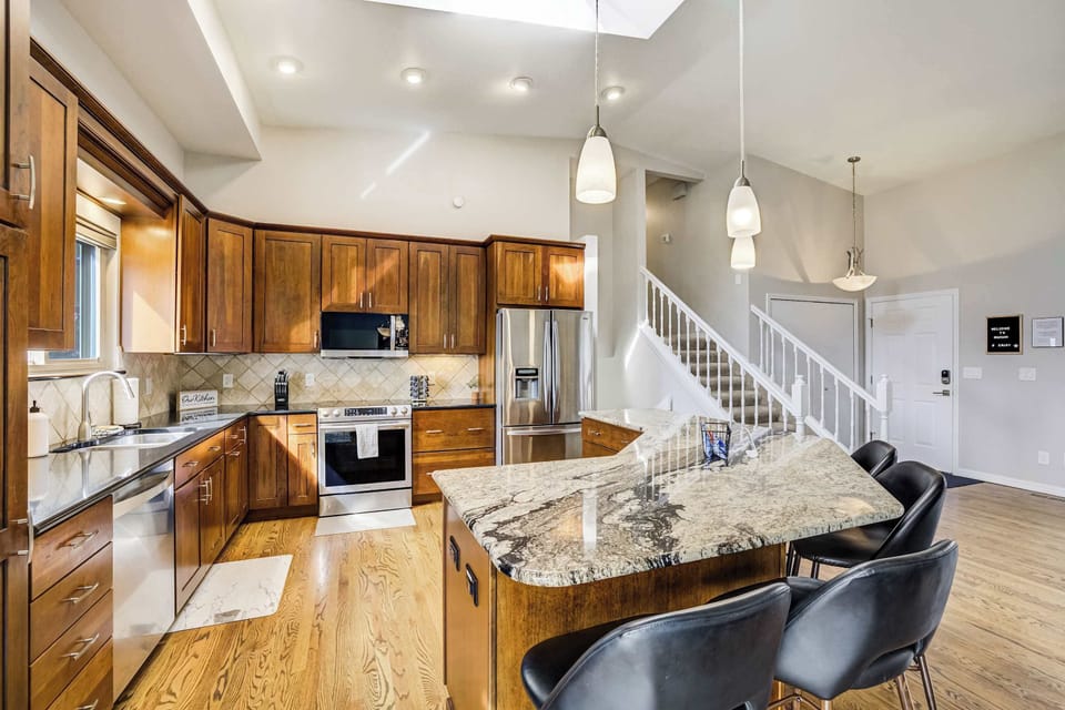 The oversized kitchen island features a unique granite profile and comfortable bar seating for four. This functional layout provides ample prep space and a social atmosphere for enjoying snacks or casual morning coffee.