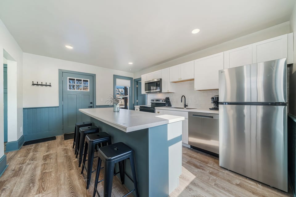 Sleek kitchen design with plenty of storage and a central island for dining. Stainless steel appliances include a microwave, oven, dishwasher, and coffee maker. Features a view of the backyard for a pleasant cooking experience.