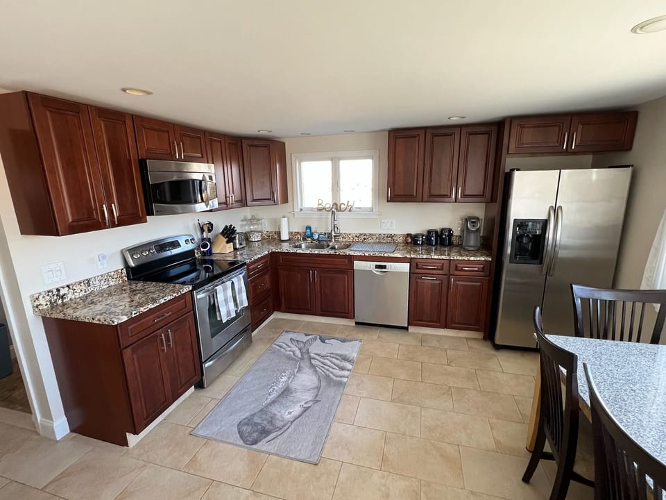 Stainless appliances, tile floor, kitchen table, and island for family mealtime