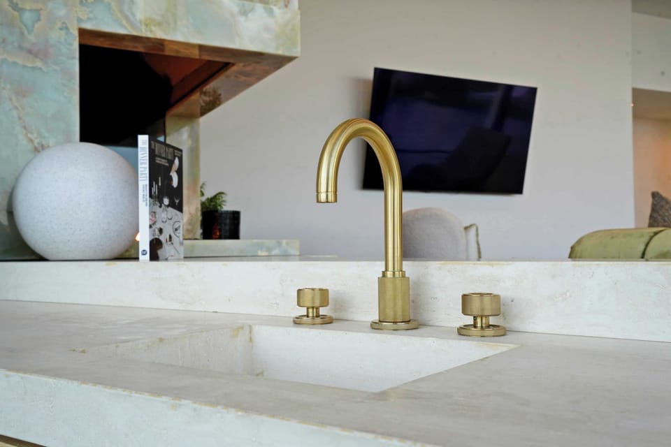 Sleek brass faucet atop a polished stone countertop, a statement of modern elegance.