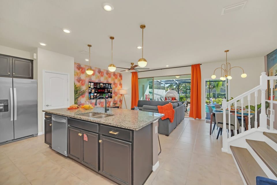 Bright open kitchen with island, modern lighting, and pool view.