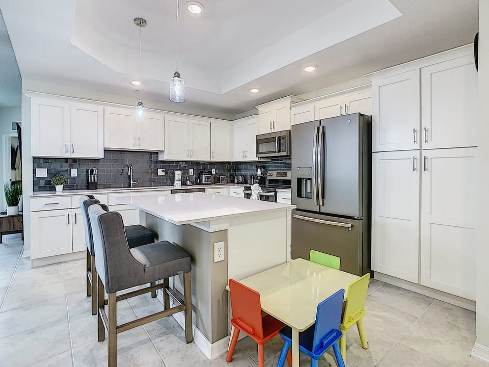 Kitchen | Modern appliances, stocked with cooking essentials + counter seating for two adults and children.